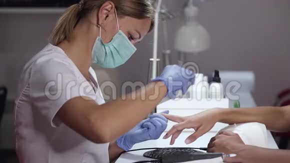 戴面具的指甲师为美容院的顾客做指甲视频的预览图