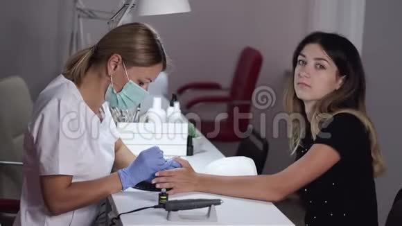 戴面罩的指甲师傅为美容院的女人修指甲视频的预览图