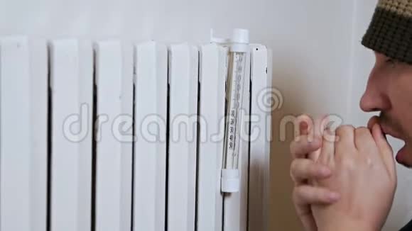 一个人在靠近电池的冬天测量房子的空气温度弱发热差穿着暖和的衣服视频的预览图