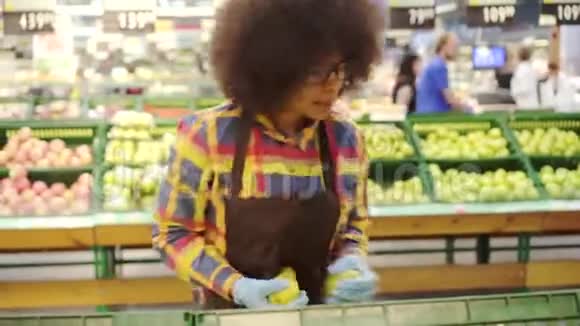 精力充沛的超级市场雇员非洲裔美国妇女有非洲发型整理水果视频的预览图
