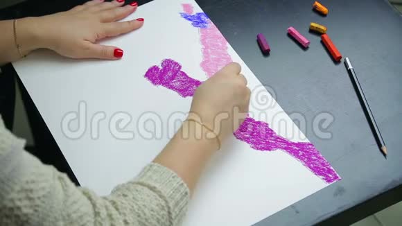 日落时分女人的手在白纸上画着紫色的彩纸视频的预览图