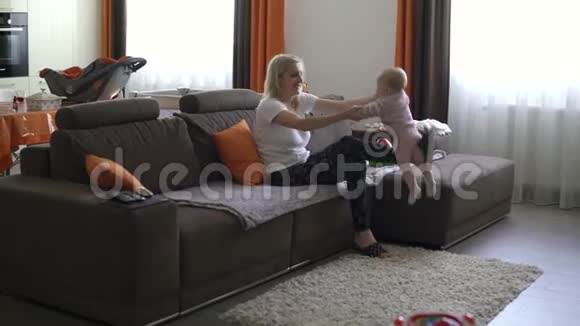 妈妈在沙发上和她的小女儿玩视频的预览图