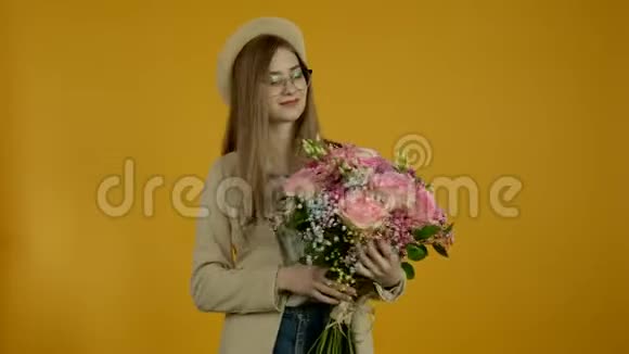 戴眼镜的年轻时尚女士微笑着嗅着花朵视频的预览图