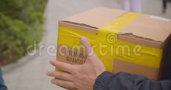 留胡子的白种人送货员双手把箱子装在背包里在户外的城市里运送视频的预览图
