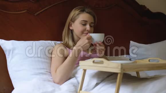 美丽的女士在床上享受早咖啡酒店客房服务周末视频的预览图