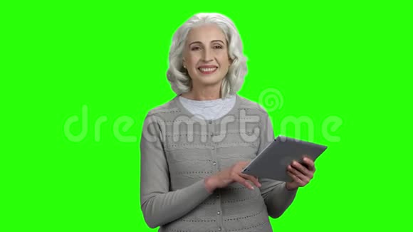 年长的女人拿着数字平板电脑和相机交谈视频的预览图