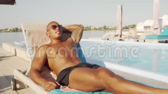 英俊的非洲运动员在海滩游泳池附近休息视频的预览图