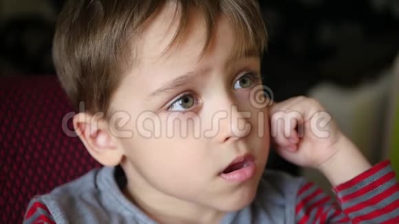 一个忧郁的男孩把他的手放在耳朵上的画像视频的预览图