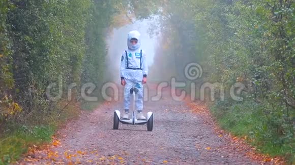 一个穿着白色西装的男孩沿着雾蒙蒙的道路在陀螺仪上移动视频的预览图