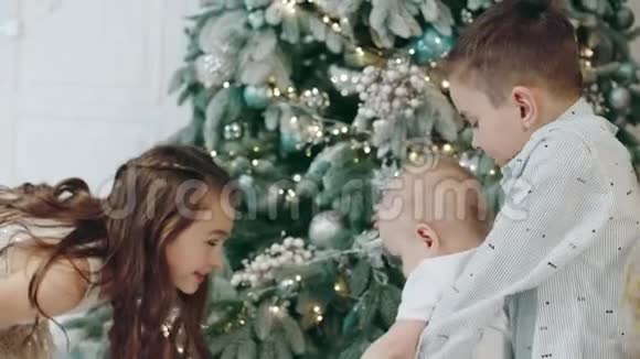 三个可爱的孩子在客厅的圣诞树上走来走去视频的预览图