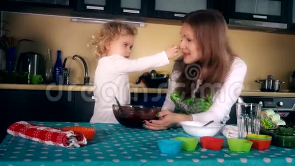 妈妈和女儿把巧克力面团放在鼻子上快乐的家庭女孩视频的预览图
