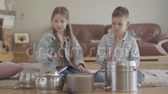 这幅画是一对可爱的兄弟姐妹两个正在演奏的音乐家用大勺子敲打着锅碗瓢盆大笑起来视频的预览图