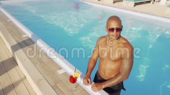 英俊的非洲男人在游泳池里喝鸡尾酒视频的预览图