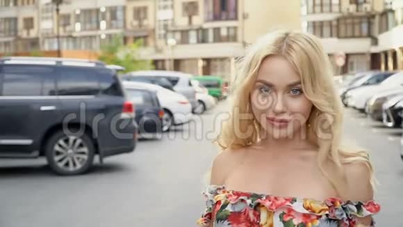 穿着夏装的金发美女在停车场摆姿势摄像机连线妇女步态视频的预览图