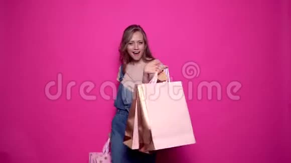 欢快的年轻女子手拿着五颜六色的购物袋跳舞视频的预览图