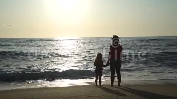 小女孩和妈妈站在日落海滩视频的预览图