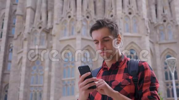 年轻的旅行者穿着格子衬衫在巴塞罗那市散步使用智能手机男性在西班牙旅行慢吞吞的视频的预览图