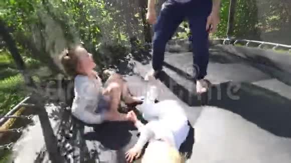 父亲在院子里的蹦床上和孩子儿子和女儿玩手持射击视频的预览图
