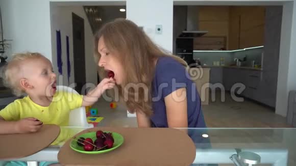 可爱的儿子用樱桃浆果喂养他的母亲平滑相机运动视频的预览图