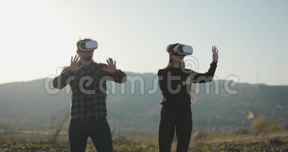 胡子男女孩使用VR耳机显示与耳机虚拟现实游戏两个人使用VR头盔视频的预览图