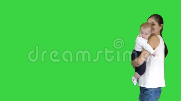 快乐的妈妈和可爱的孩子宝贝儿子挥舞着双手在绿色的屏幕上向相机问好色度键视频的预览图