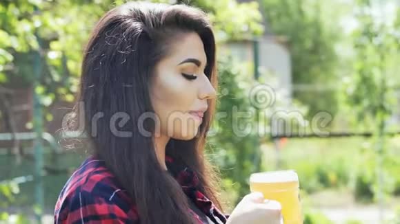 年轻快乐的女人在花园里烧烤时用玻璃喝啤酒解渴视频的预览图