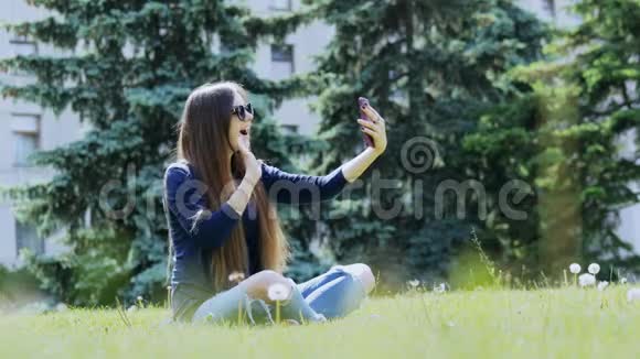 吸引人的年轻女子视频呼叫或拍摄夏季公园的视频视频的预览图