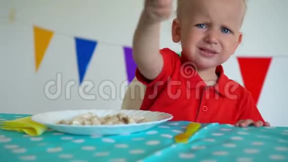 心烦意乱的蹒跚学步的孩子男孩坐在桌子旁吃饺子万向节运动视频的预览图