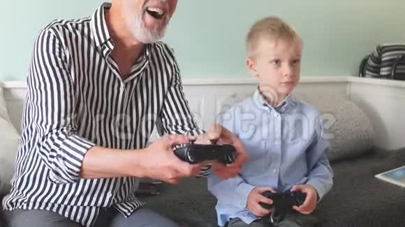情绪化的祖父和他的孙子玩电脑游戏和操纵杆视频的预览图