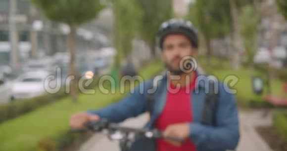 成人白种人送货员的特写照片背包里走着骑着脚踏车微笑着看着摄像机视频的预览图