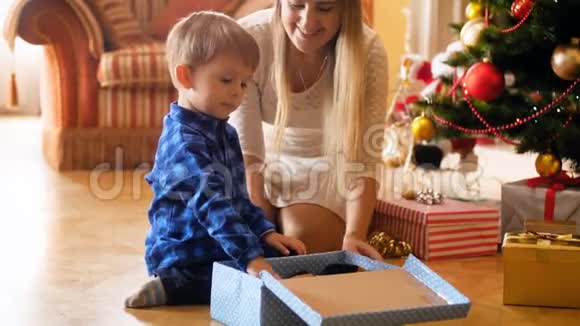 可爱的小男孩从圣诞老人那里打开他的礼物盒拿出玩具毛绒狗家庭捐赠和视频的预览图