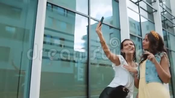 两个女朋友姐妹走在新大楼办公室附近城市拍照女孩们玩得开心散步笑跳带视频的预览图