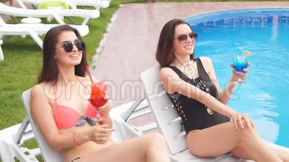 两个女朋友花时间在泳池边放松喝新鲜的鸡尾酒视频的预览图