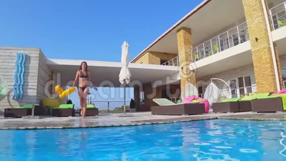 快乐苗条的女孩穿着带充气戒指的泳衣暑假在昂贵的度假胜地的游泳池里潜水视频的预览图