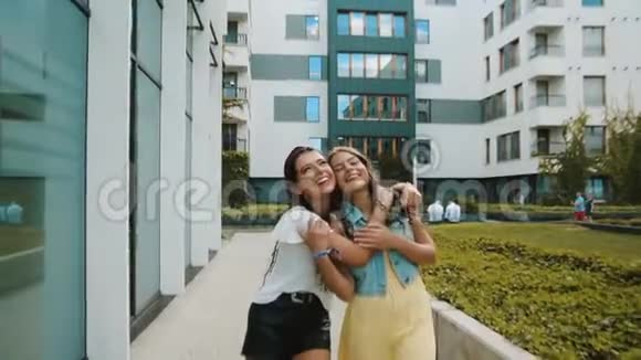 两个女朋友姐妹走在新大楼办公室城市附近女孩玩得开心走路笑跳游客走着走着视频的预览图