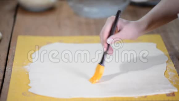 面包房桌子上的一层大面团用刷子润滑视频的预览图