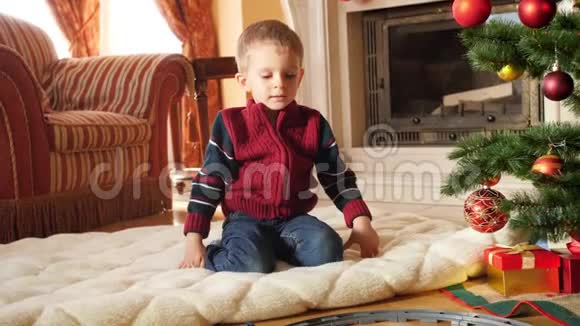 小蹒跚学步的男孩在客厅的圆圈铁路上看玩具火车的4k镜头儿童接受礼物视频的预览图
