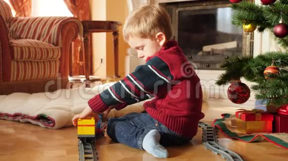 小男孩从圣诞树下的砖块和积木上建造玩具火车和铁路的4k镜头儿童视频的预览图