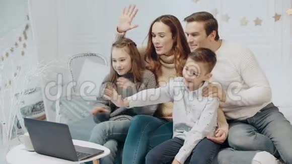 快乐的父母和孩子在电脑屏幕前挥动双手视频的预览图