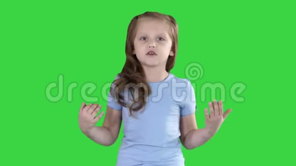 小女孩走路和镜头说话在绿色屏幕上做手势色度键视频的预览图