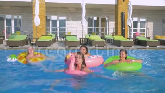 夏天游泳池里的乐趣穿着长发泳衣的快乐女友在蓝色的游泳池里嬉戏泼水视频的预览图