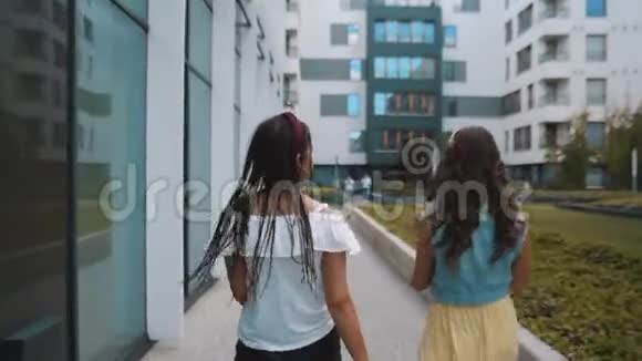 两个女朋友姐妹走在新大楼办公室城市附近女孩玩得开心走路笑跳游客走着走着视频的预览图