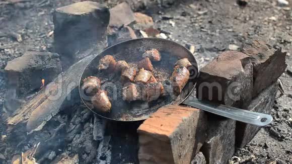 一个人在森林里的火堆上用平底锅烤香肠野餐视频的预览图