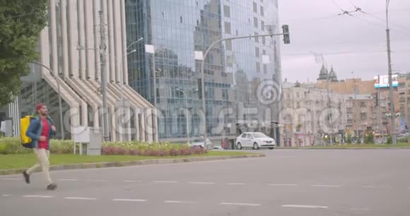 带背包的成年白人送货员在城市户外横穿街道的照片视频的预览图