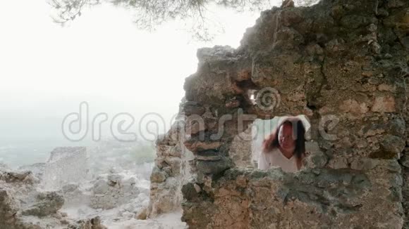 旅游妇女透过窗户四处张望这座古老的山城的建筑被毁坏了走进来的旅游妇女视频的预览图