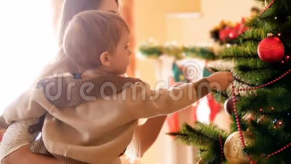 4k的小男孩帮助他妈妈用圣诞饰品和玩具装饰圣诞树的镜头家庭准备和视频的预览图