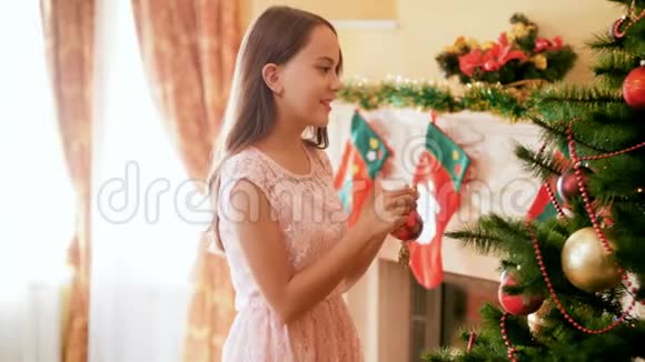 4k镜头美丽的年轻女孩穿着礼服在客厅用装饰品和花环装饰圣诞树家庭视频的预览图