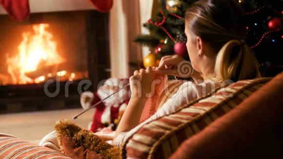 4k视频圣诞前夜年轻女子坐在壁炉旁织羊毛衫人们在冬天放松视频的预览图