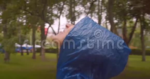 穿着蓝色雨衣用舌头接雨滴的年轻白种人女性特写镜头视频的预览图