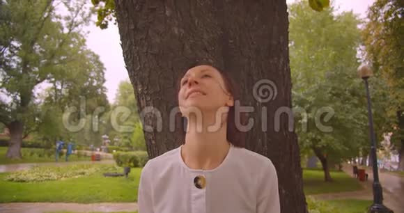 室外公园树下躲雨的年轻白人女性特写照片视频的预览图